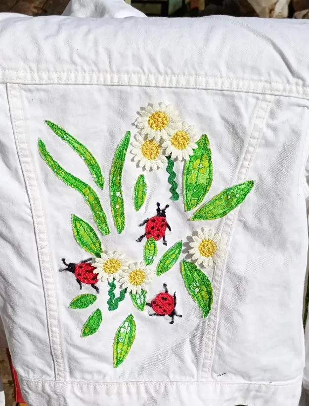 White denim jacket hand-embroidered with daisies and ladybirds